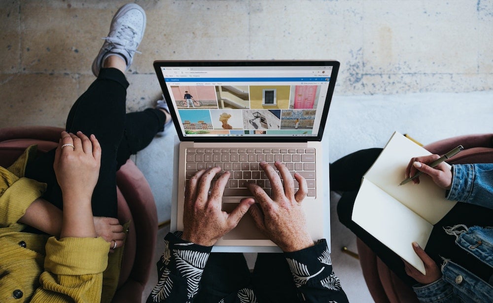 3 people work from an open laptop, selecting colour images