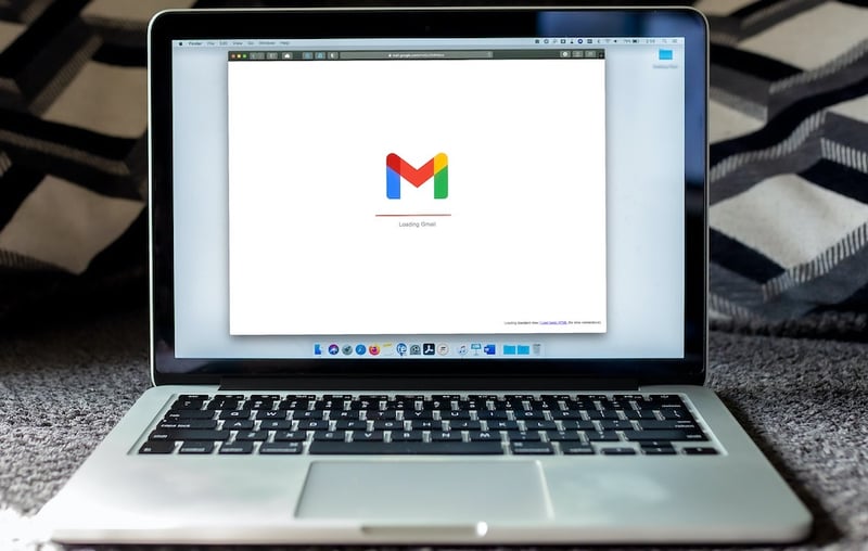 A mac laptop sits open with gmail loading on the screen