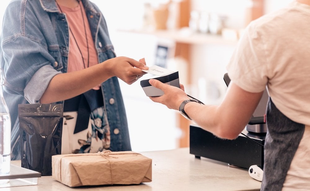 A customer hands a card to a shop cashier to pay for goods