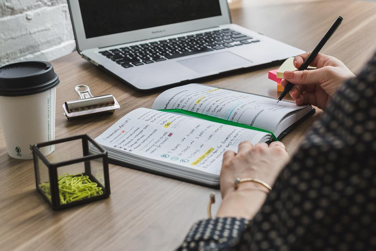 Marketing professional uses diary and computer to make SEO plan.