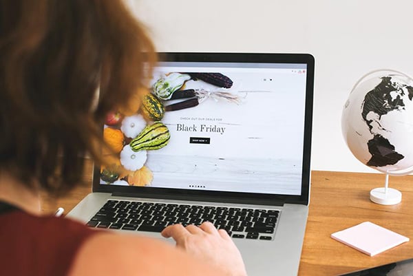 Woman working on a laptop  to create Black Friday themed marketing