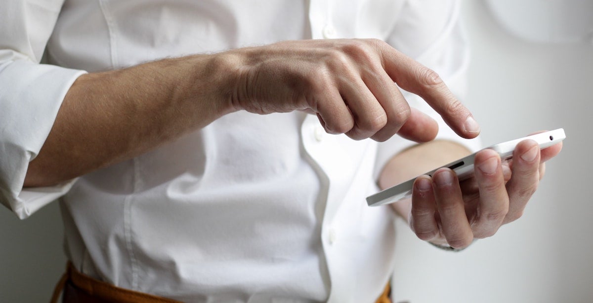 Man in a white shirt scrolls on his cellphone