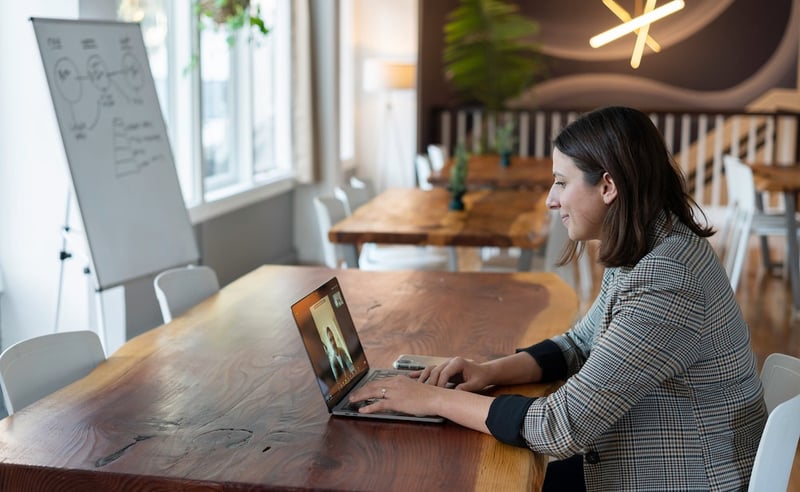 a woman uses a video conferencing software at an open-plan office space