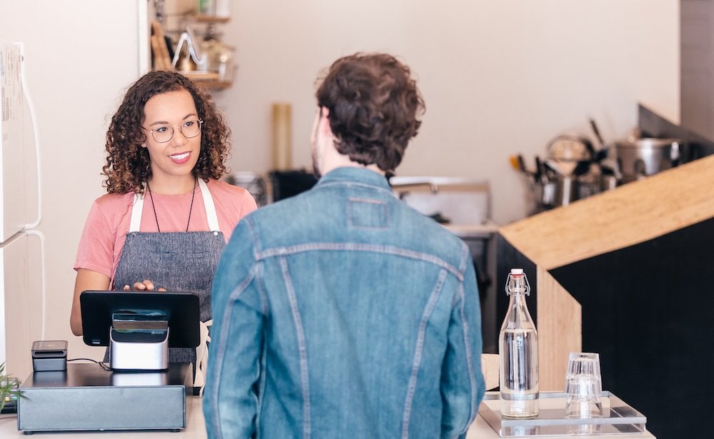 a customer faces a smiling cashier in a physical store